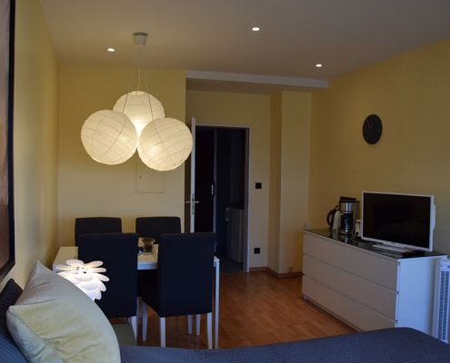 Blick vom Bett in den Wohnbereich mit Sitzgelegenheit und und Sideboard in der zweiten Gästewohnung in der Fritz-Erler-Allee 120
