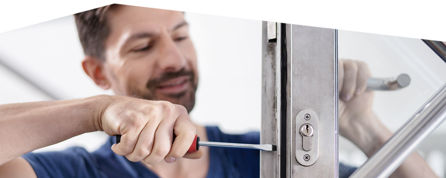 Handwerker bearbeitet mit dem Schraubenzieher ein Fenster