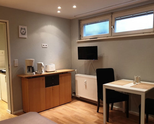 Kommode mit Kaffeemaschine, Wasserkocher und Toaster sowie Zweier-Sitzgelegenheit in der Gästewohnung Nahariyastr. 36