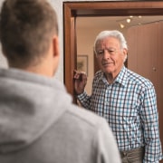 geöffnete Wohnungstür mit einem älteren Mann im Türrahmen, der einem Besucher gegenübersteht