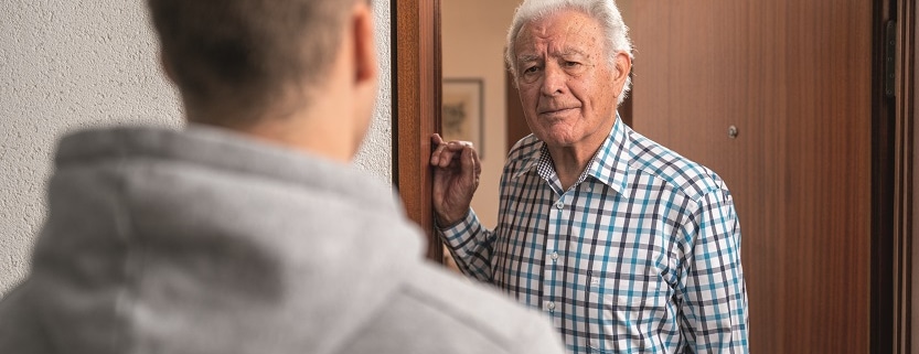 geöffnete Wohnungstür mit einem älteren Mann im Türrahmen, der einem Besucher gegenübersteht